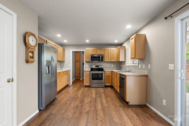 kitchen with light countertops, baseboards, appliances with stainless steel finishes, and dark wood-type flooring