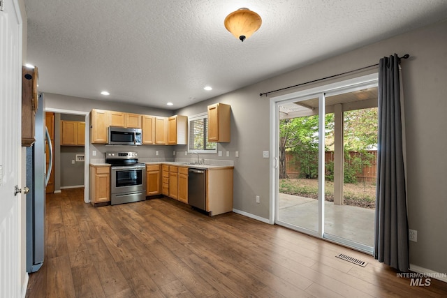 kitchen with baseboards, dark wood-type flooring, light countertops, a sink, and appliances with stainless steel finishes
