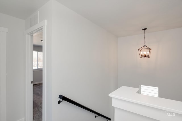 staircase featuring carpet floors and a chandelier