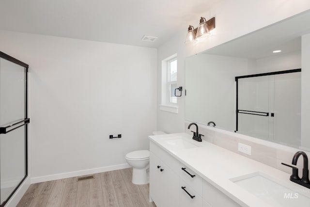 bathroom with vanity, wood-type flooring, a shower with shower door, and toilet