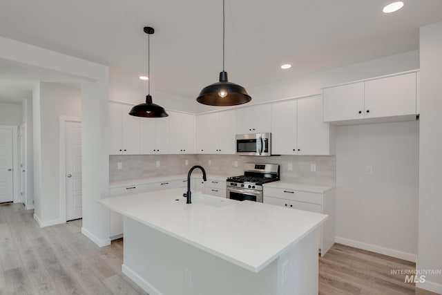 kitchen with pendant lighting, light hardwood / wood-style floors, white cabinets, and stainless steel appliances