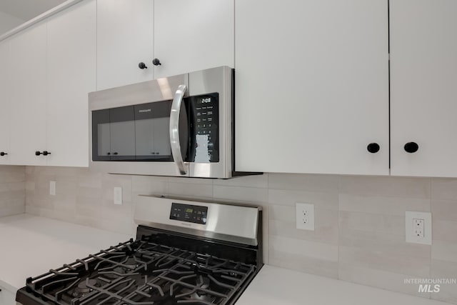 kitchen featuring tasteful backsplash, white cabinets, and range with gas stovetop