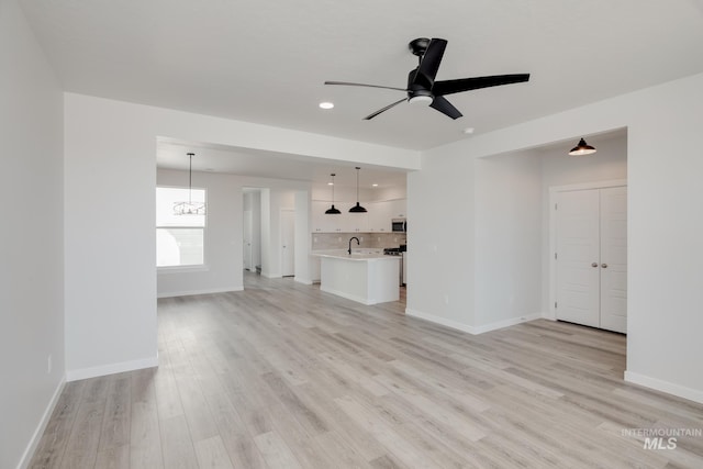 unfurnished living room with ceiling fan, light hardwood / wood-style flooring, and sink