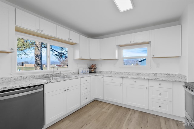 kitchen featuring appliances with stainless steel finishes, sink, white cabinets, light stone countertops, and light wood-type flooring