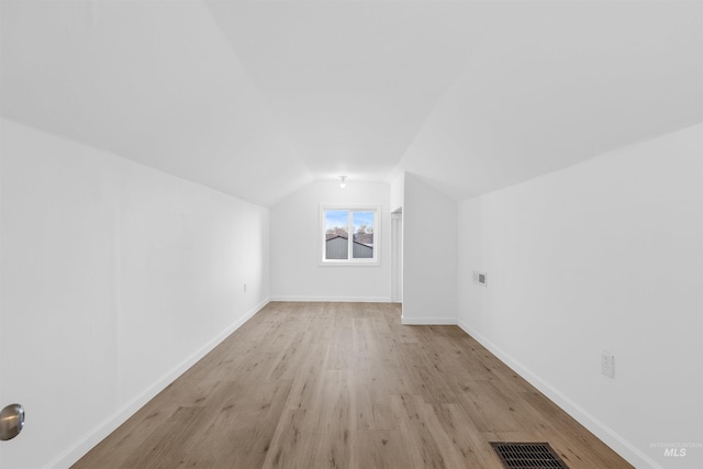 additional living space featuring vaulted ceiling and light hardwood / wood-style floors