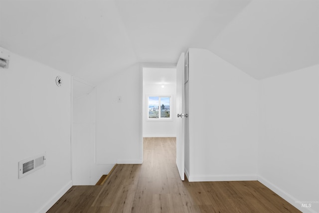 additional living space with vaulted ceiling and light wood-type flooring