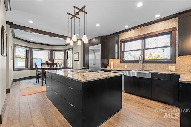 kitchen with a kitchen island, decorative light fixtures, stainless steel appliances, sink, and light hardwood / wood-style flooring