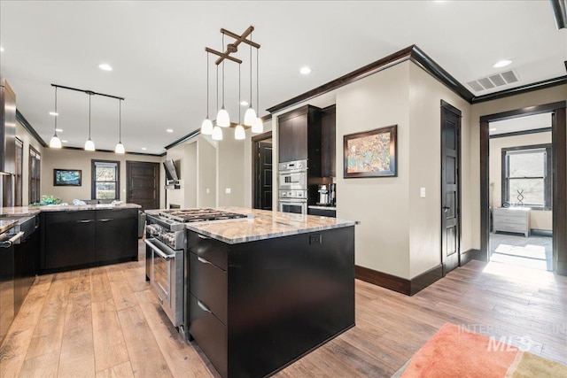 kitchen featuring decorative light fixtures, a barn door, a kitchen island, crown molding, and stainless steel appliances