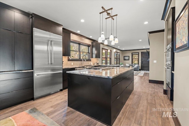 kitchen with pendant lighting, crown molding, light hardwood / wood-style flooring, stainless steel appliances, and a large island