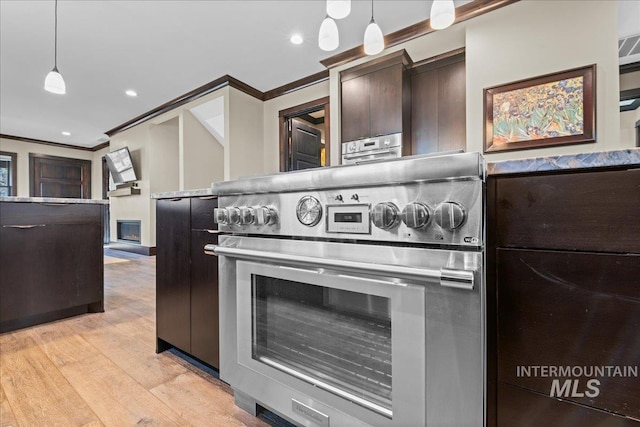 kitchen featuring light wood-type flooring, crown molding, high end stainless steel range, and decorative light fixtures