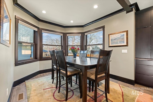 dining room with light wood-type flooring and crown molding