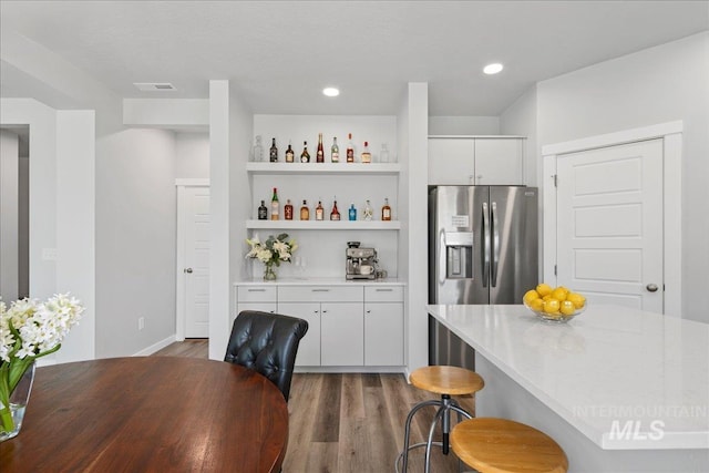 4953 W Apgar St, Meridian, ID 83646 - kitchen with stainless steel fridge, a breakfast bar area, open shelves, wood finished floors, and white cabinets