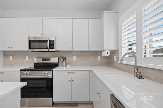 4953 W Apgar St, Meridian, ID 83646 - kitchen with stainless steel appliances, a sink, light countertops, white cabinets, and tasteful backsplash