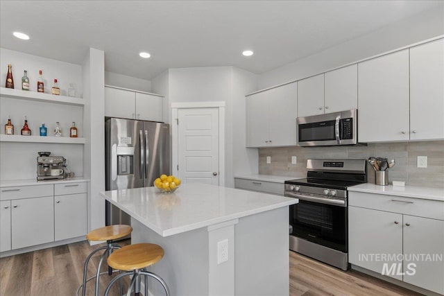 4953 W Apgar St, Meridian, ID 83646 - kitchen with stainless steel appliances, a breakfast bar, light wood-style floors, light countertops, and recessed lighting