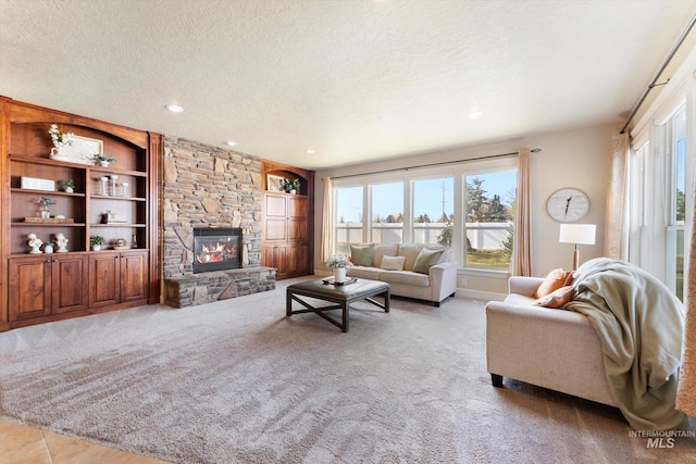 living room featuring a textured ceiling, a stone fireplace, and a wealth of natural light