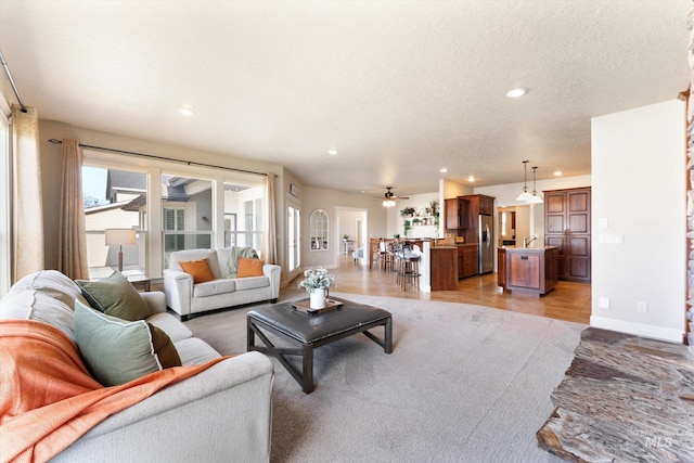 living room featuring recessed lighting, ceiling fan, a textured ceiling, and baseboards