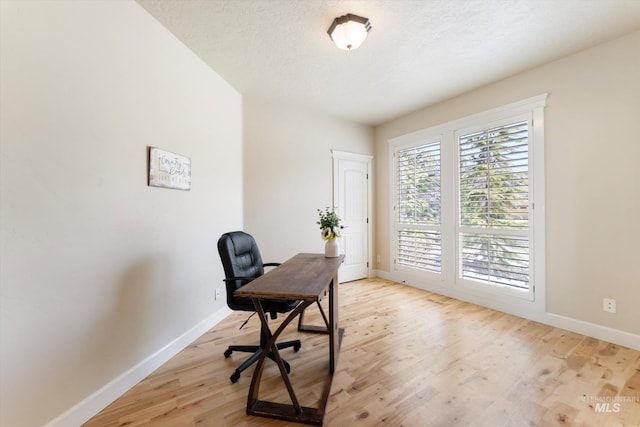 office area featuring light wood-type flooring, baseboards, and a textured ceiling