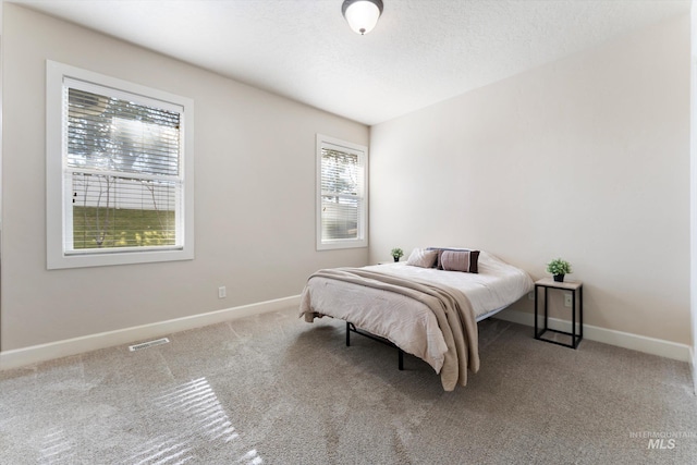 carpeted bedroom featuring visible vents, baseboards, and a textured ceiling