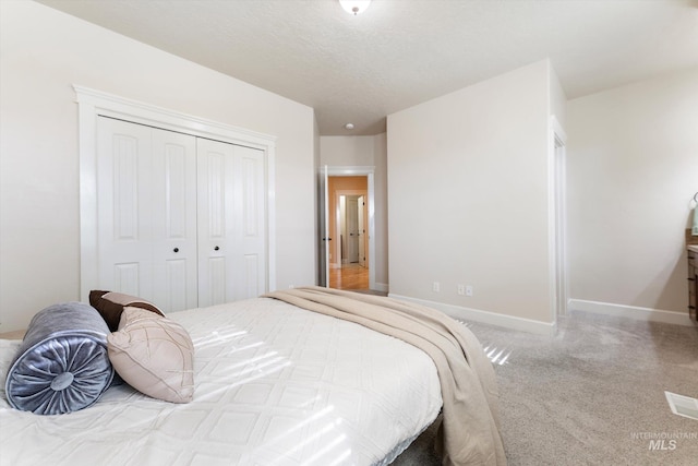 carpeted bedroom featuring a textured ceiling, a closet, and baseboards