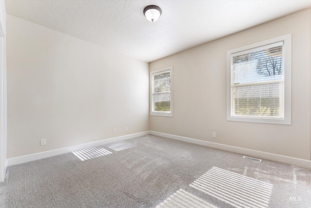 carpeted empty room with visible vents, baseboards, and a textured ceiling