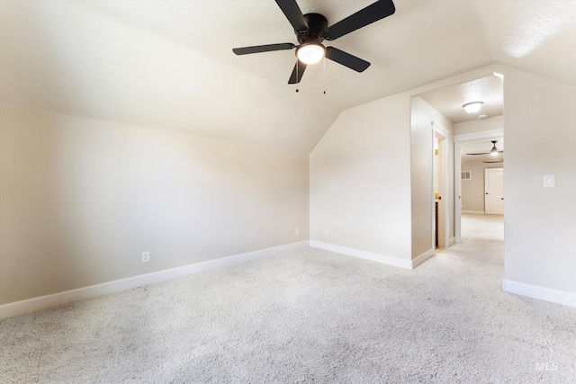 additional living space with light colored carpet, vaulted ceiling, visible vents, and baseboards