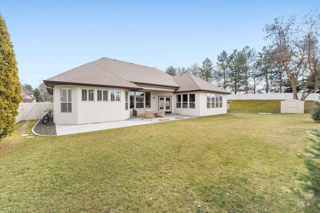 rear view of property with a yard, a patio, stucco siding, a storage shed, and a fenced backyard