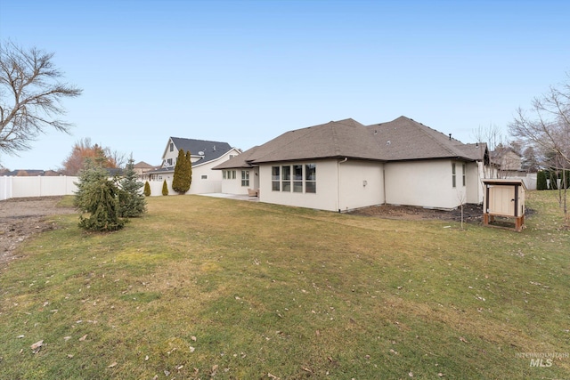 back of property with an outdoor structure, fence, a yard, stucco siding, and a shed