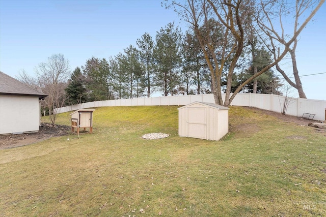 view of yard with a shed, a fenced backyard, and an outbuilding