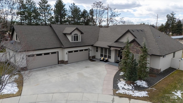 view of front of home with a garage, stone siding, concrete driveway, and stucco siding