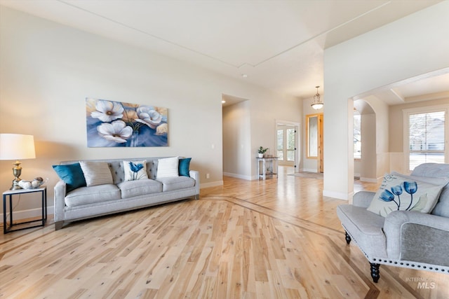 living area featuring arched walkways, wood finished floors, and baseboards