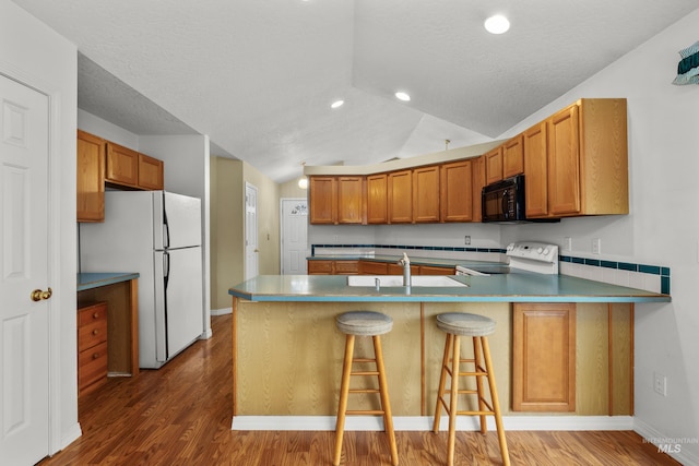 kitchen with lofted ceiling, stove, freestanding refrigerator, black microwave, and a peninsula