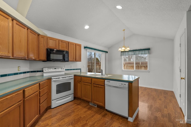 kitchen with white appliances, brown cabinets, a sink, and a peninsula