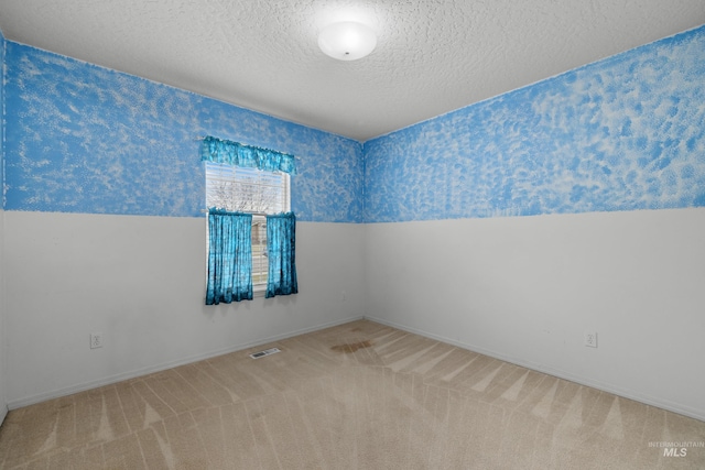 spare room with a textured ceiling and carpet