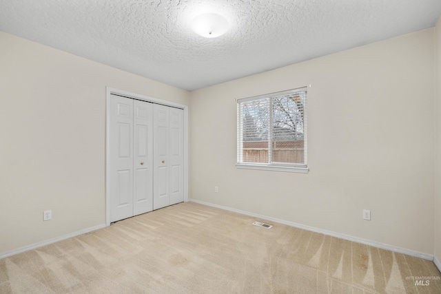 unfurnished bedroom with a closet, light colored carpet, visible vents, and baseboards