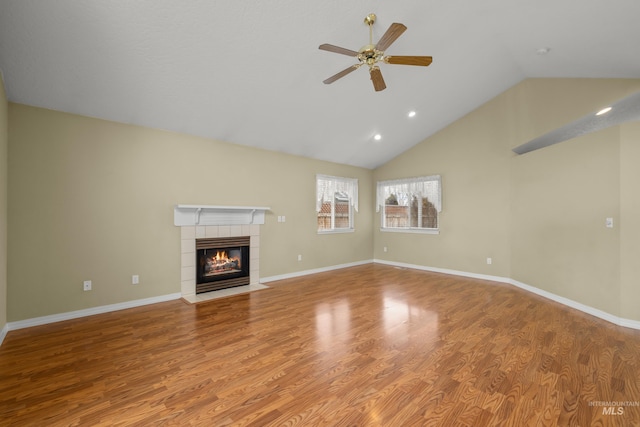 unfurnished living room with a fireplace, lofted ceiling, a ceiling fan, wood finished floors, and baseboards