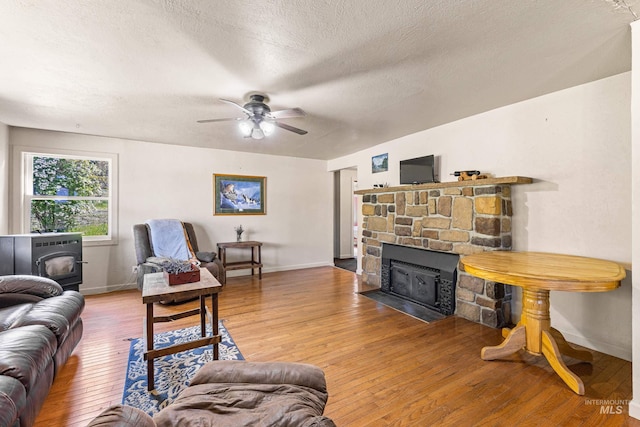 255 Seven U Ranch Rd, Lucile, ID 83542 - living area featuring a wood stove, light wood finished floors, baseboards, and a textured ceiling