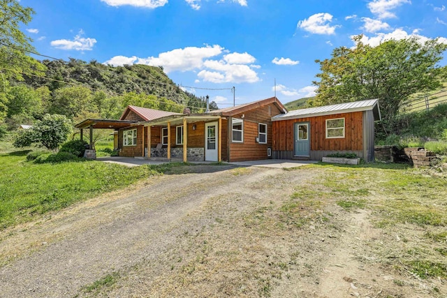 255 Seven U Ranch Rd, Lucile, ID 83542 - view of front of house with a porch, metal roof, driveway, stone siding, and board and batten siding