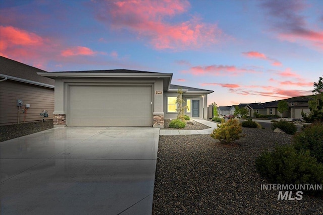 5707 W Elk Trail St Unit 630, Boise, ID 83714 - view of front facade with concrete driveway, a garage, stone siding, and stucco siding