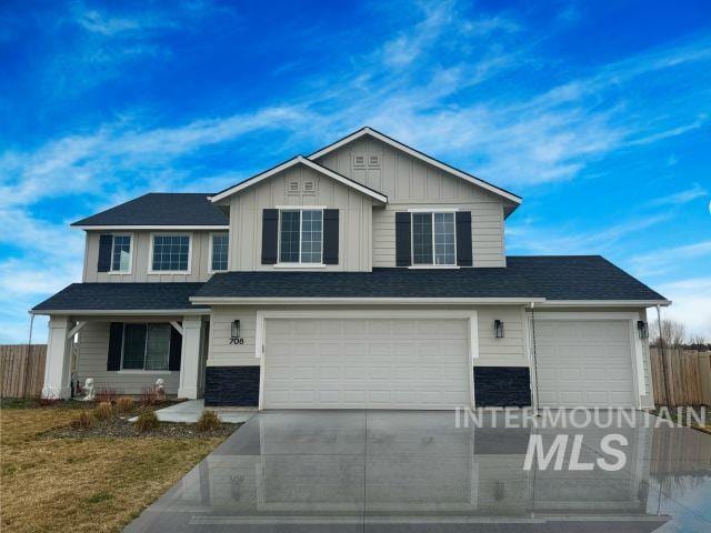 view of front of property with driveway, an attached garage, board and batten siding, and fence