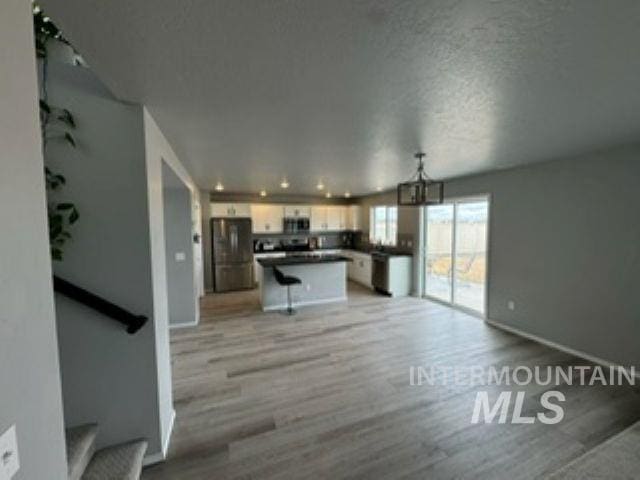 interior space featuring baseboards, a textured ceiling, stairs, and light wood finished floors