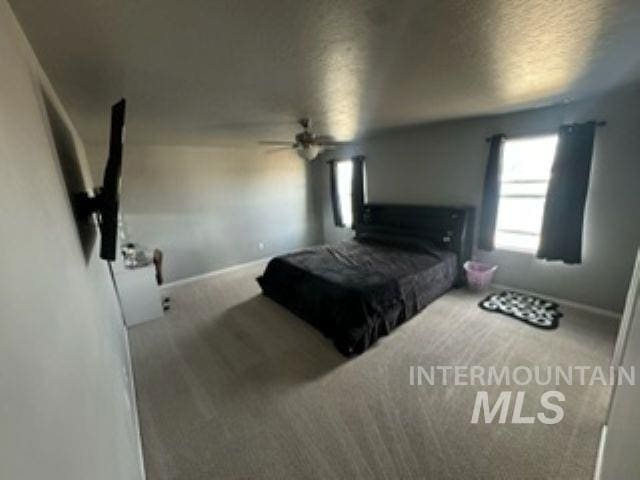 carpeted bedroom featuring a textured ceiling, baseboards, and ceiling fan