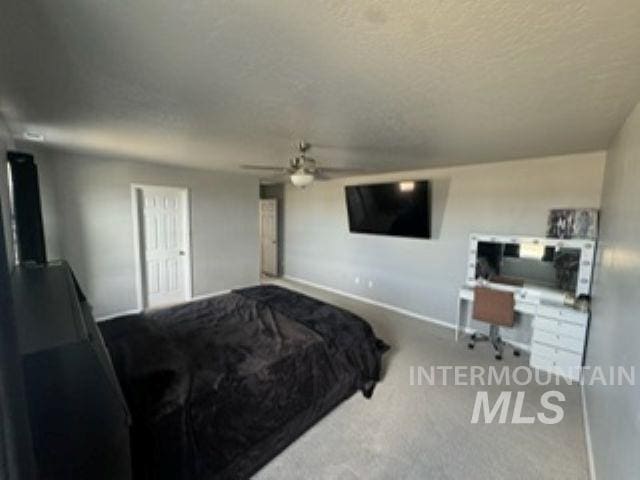 carpeted bedroom featuring a ceiling fan, baseboards, and a textured ceiling