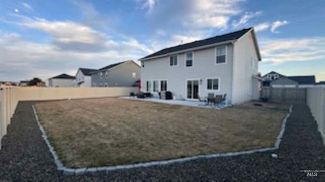 back of property featuring a yard, a patio, and a fenced backyard