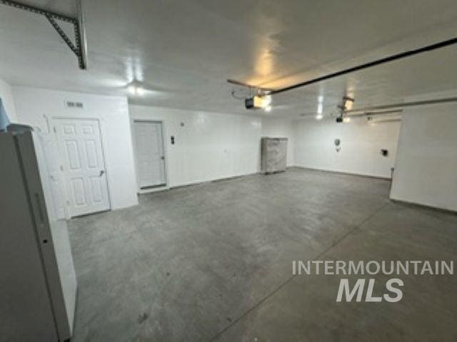 garage with a garage door opener and freestanding refrigerator