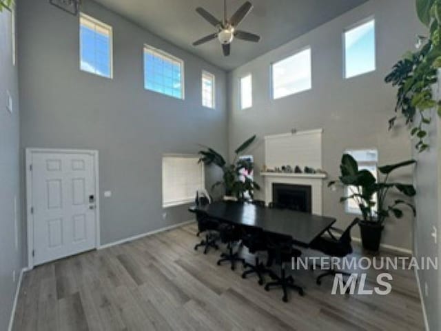 dining room with a fireplace, baseboards, a ceiling fan, and wood finished floors