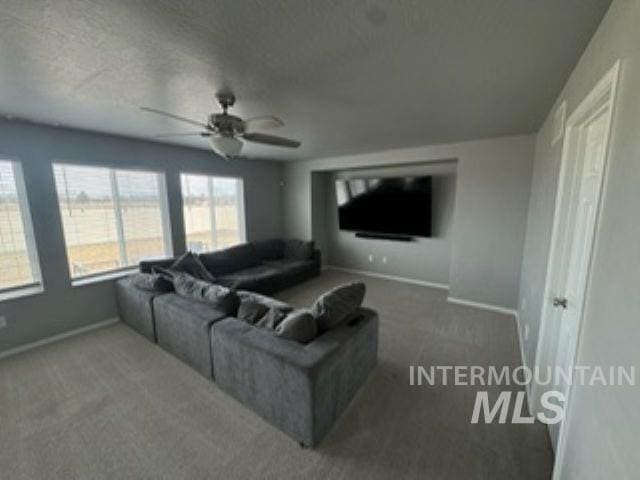 living area with baseboards, carpet floors, and a textured ceiling