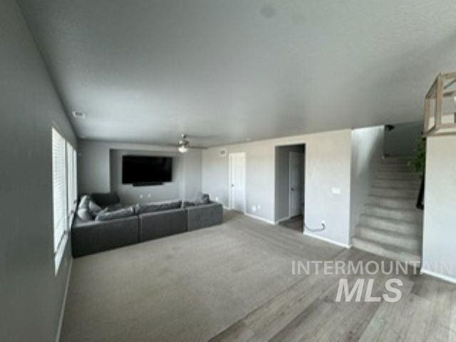 living area featuring wood finished floors, a ceiling fan, and baseboards