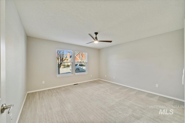 empty room featuring light carpet, ceiling fan, and a textured ceiling