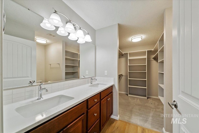 bathroom featuring hardwood / wood-style flooring, decorative backsplash, vanity, and a textured ceiling