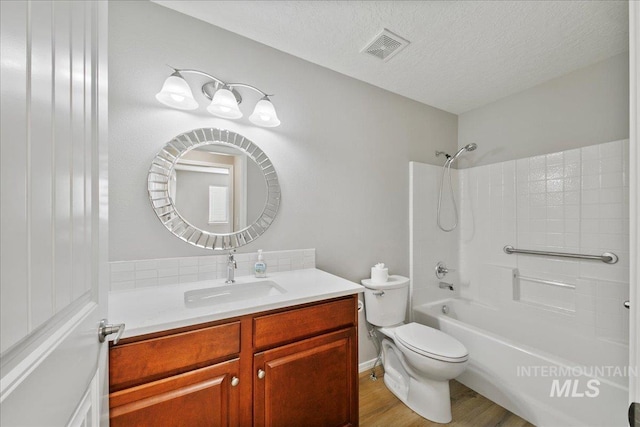 full bathroom with hardwood / wood-style floors, vanity, toilet, tub / shower combination, and a textured ceiling